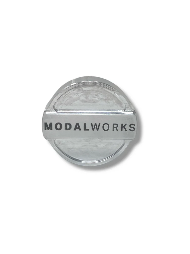 Round metallic object with 'Modalworks' branding on a white background