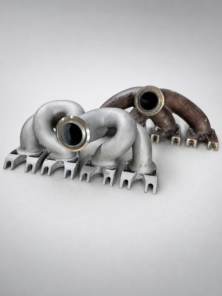 Three-quarter view: ModalWorks M177 equal-length exhaust manifold beside the OEM cast manifold